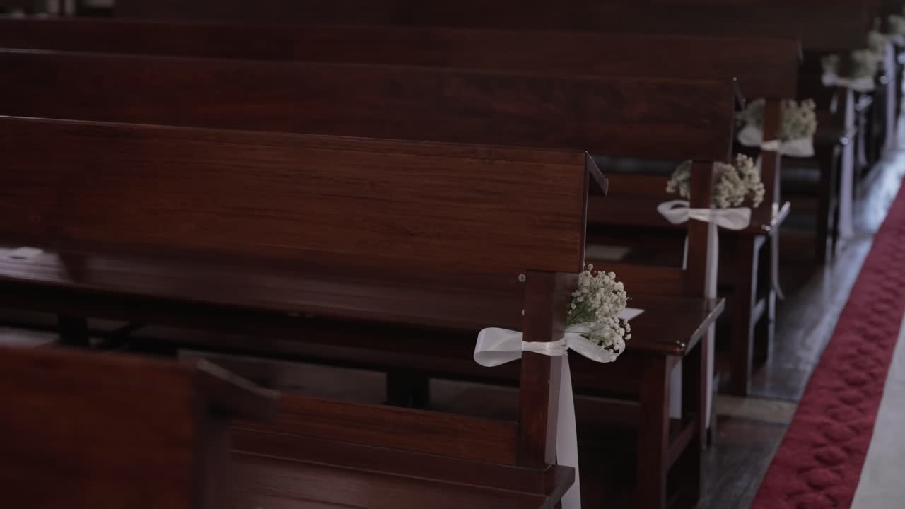 wooden church benches adorned for wedding with white bows and delicate flowers