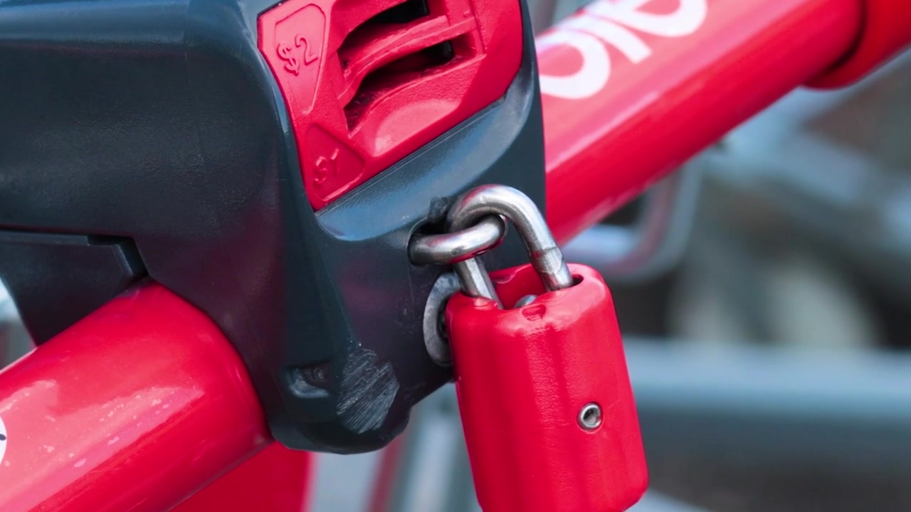Primo piano di un lucchetto rosso per bicicletta che assicura una catena.
