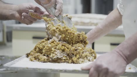 Slow-motion-panning-shot-of-a-dough-for-candy-on-a-tablet-held-by-a-baker-while-using-a-spatula-to-stack-more-dough