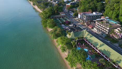 Smooth-aerial-top-view-flight-Beach-Village-Huts-Resort,-tropical-Bungalows-on-Mountainous-Island-Thailand-2022