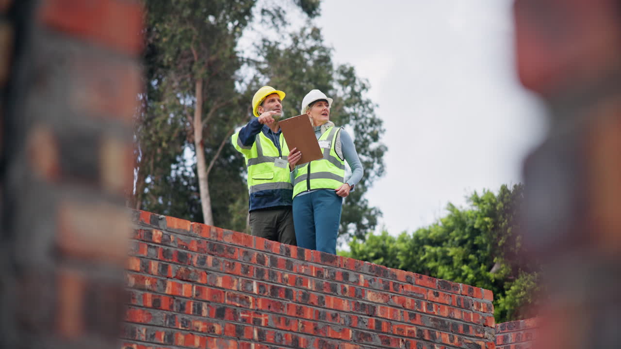 Construction workers inspecting a brick wall