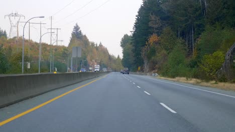 driving on the highway through forest trees and rugged canyon on a sunny day in autumn