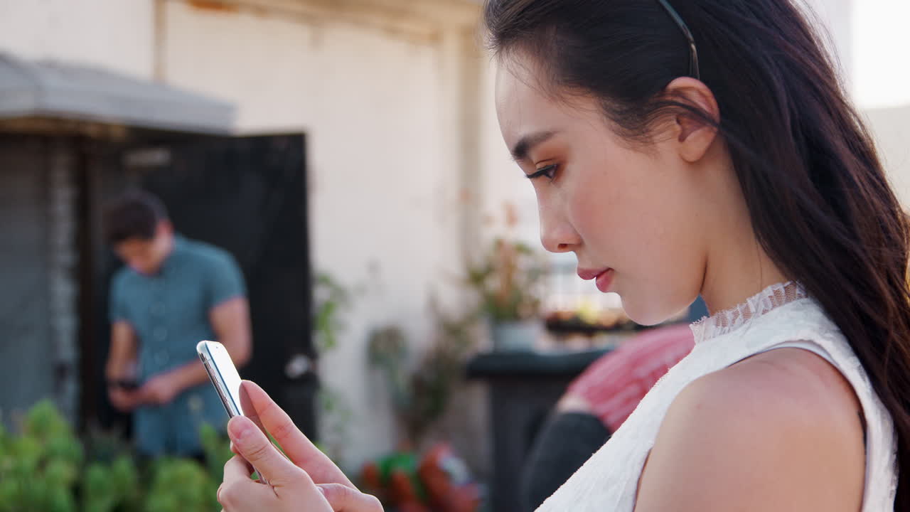 Người phụ nữ tại bữa tiệc đang sử dụng điện thoại di động với cảnh quan thành phố làm nền