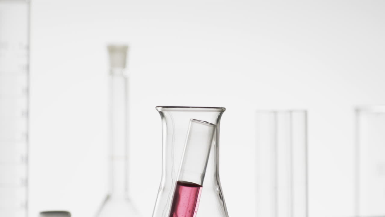 Video of glass laboratory test tube with pink liquid in beaker with copy space on white background