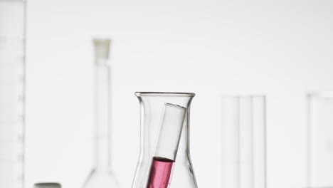 vídeo de un tubo de ensayo de laboratorio de vidrio con líquido rosado en un vaso con espacio de copia sobre fondo blanco