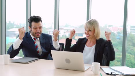 two happy business people celebrate at office