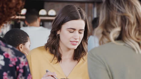 Group-Of-Friends-Meeting-For-Meal-In-Restaurant-Sitting-Around-Table-Talking