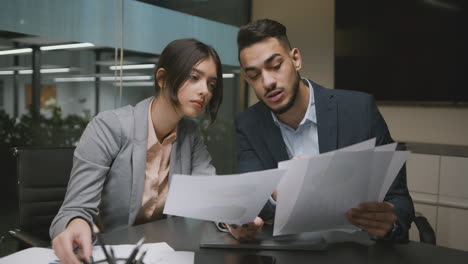 two business professionals collaborating and analyzing documents in an office meeting