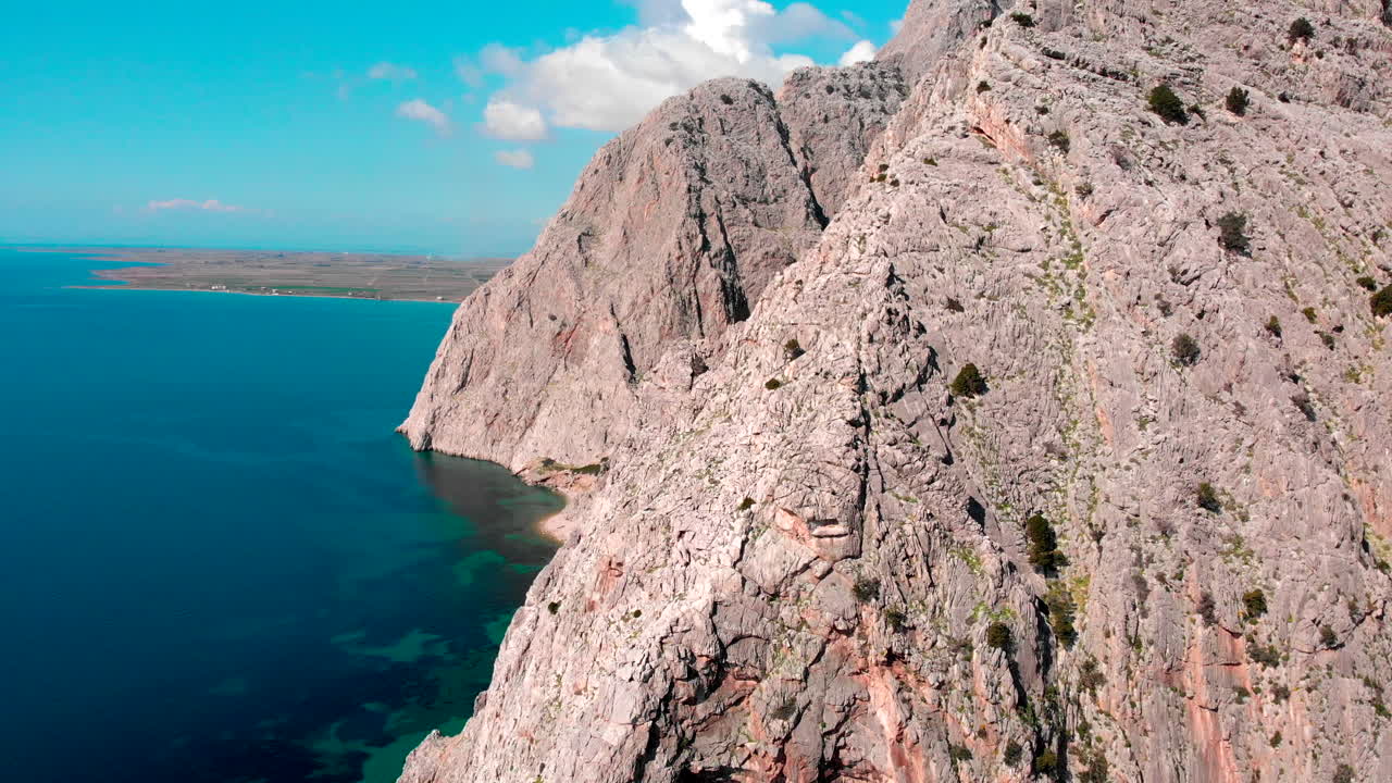 Mountain Cliffs Surrounded By The Beautiful And Calm Blue Ocean On A Sunny Summer Day In Greece. - aerial drone shot