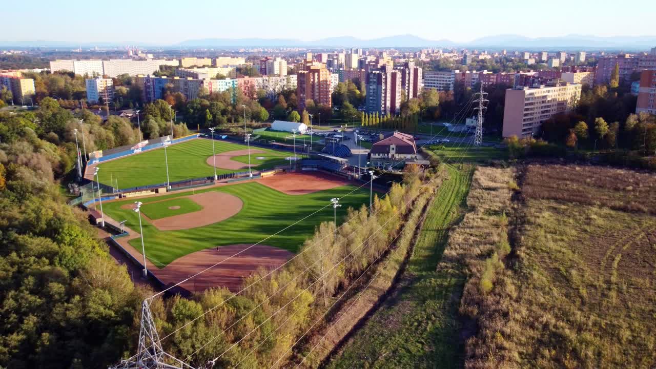 Drone pullback pan reveals autumn landscape around Arrows Ostrava baseball diamond, highlighting the vibrant fall scenery