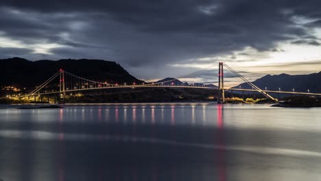 vista nocturna del puente gjemnessund, un puente que cruza el estrecho gjemnessundet entre el continente y la isla de bergsøya en el municipio de gjemnes en el condado de møre og romsdal, noruega