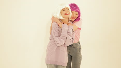 two women hugging in purple sweatshirts with pink and white wigs