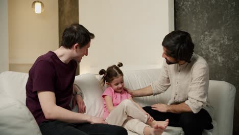 pareja gay o tío sentado con hablando con la niña en el sofá