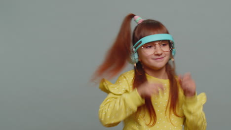 happy preteen child girl kid listening music via headphones and dancing disco fooling around