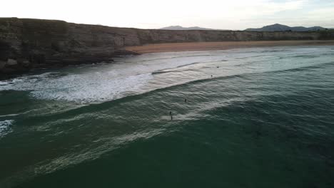 Group-of-ocean-surfers-waiting-for-wave-to-come-at-cliffed-coastline