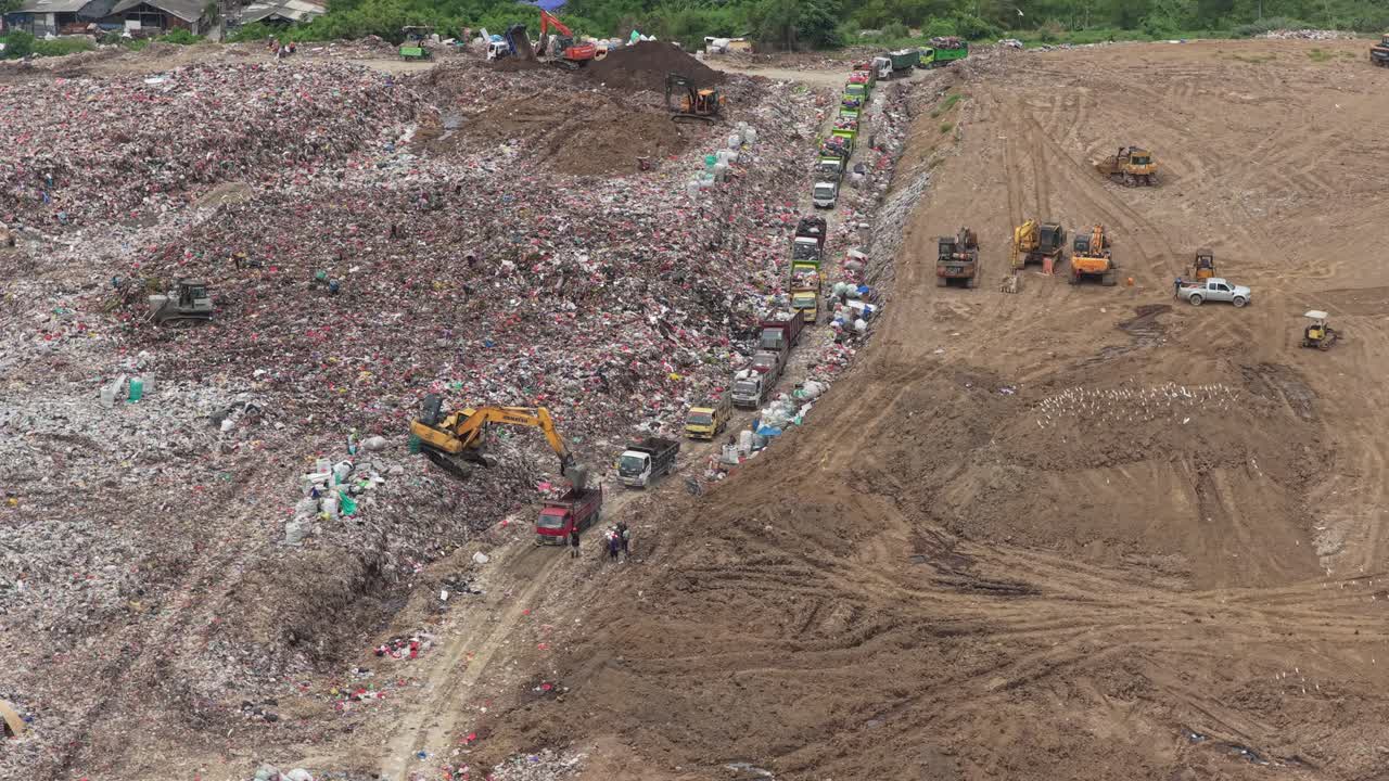 Veduta aerea di camion ed escavatori in un'enorme discarica a Bali