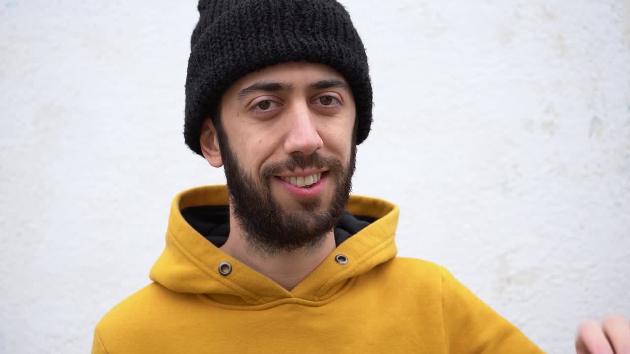 Bearded Man Waves His Hand Saying Goodbye With A Smile. Close Up