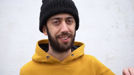 bearded man waves his hand saying goodbye with a smile. close up