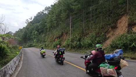 group of motorcyclists riding on a winding forest road