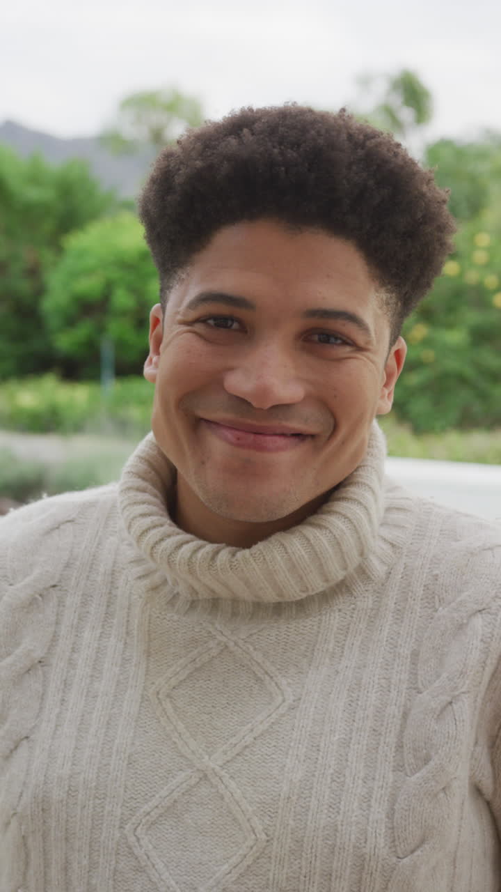 video vertical de un hombre biracial feliz sonriendo a la cámara