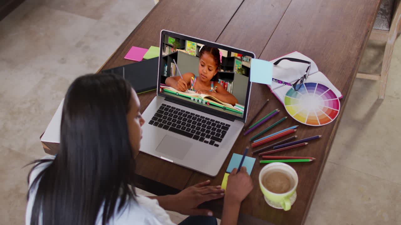 Maestra caucásica usando computadora en videollamada con una alumna, escribiendo