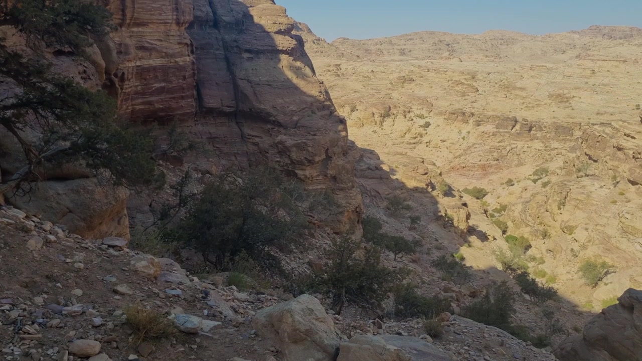 Robust ørkenlandskap i dalene nær Petra, Wadi Musa, Jordan, med sparsom vegetasjon, dramatiske sandsteinsformasjoner og avsidesliggende turstier som viser den ville skjønnheten i den jordanske ørkenen