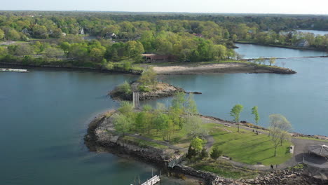 An-aerial-view-over-a-quiet-pond-which-is-surrounded-by-green-trees-on-a-sunny-day