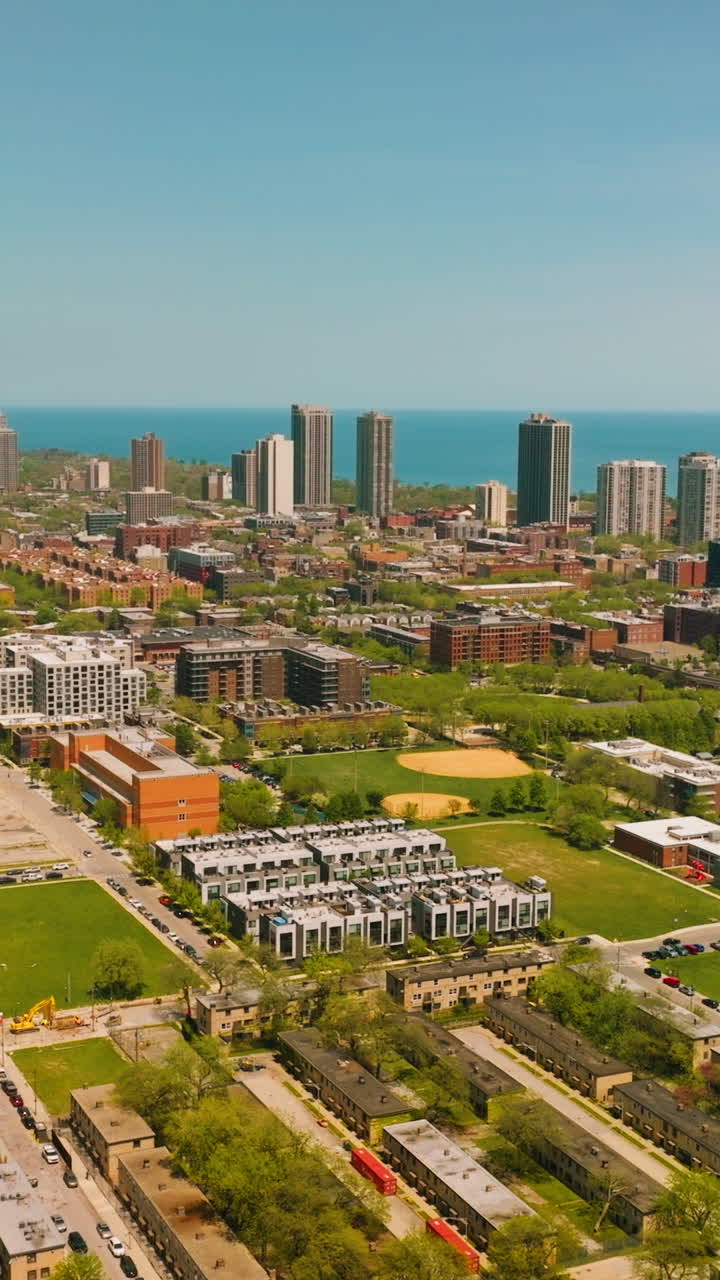 Scenic view of the residential area with low buildings and roads. Skyscrapers at backdrop against blue Michigan Lake. Vertical video