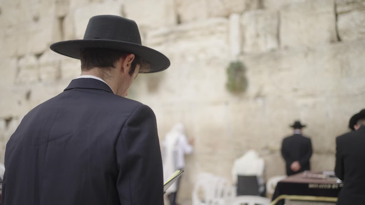 Religious Orthodox Jewish Men Praying With Torah At Western Wall In Jerusalem, Israel. medium shot, rear view
