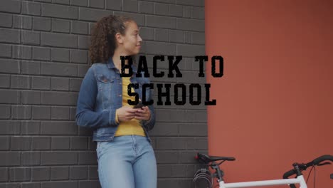 una feliz mujer biracial en la ciudad, al lado de una bicicleta, usando un teléfono inteligente