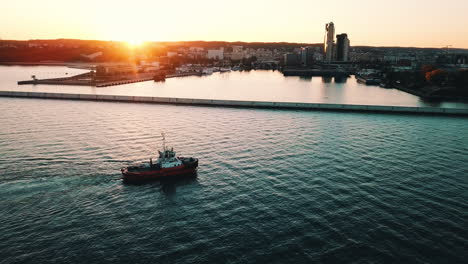 Drone-flying-around-fishing-boat-near-bay-at-the-sunset