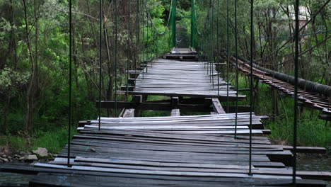 Viejo-Puente-De-Madera-Dañado-Con-Listones-Faltantes-Sobre-Un-Río-En-El-Bosque