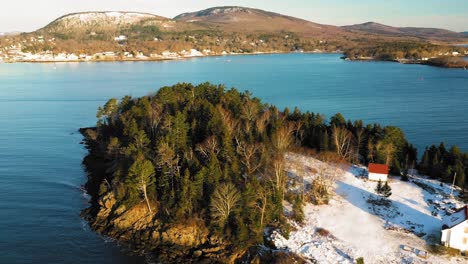 flying backwards along the shore of a snow covered curtis island to reveal the lighthouse and keepers house