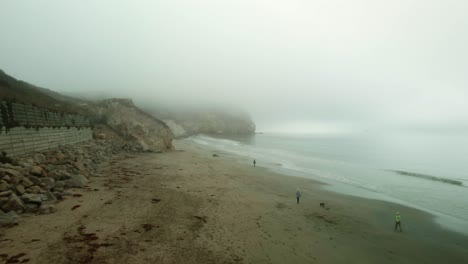 gente caminando en la playa en un día de niebla