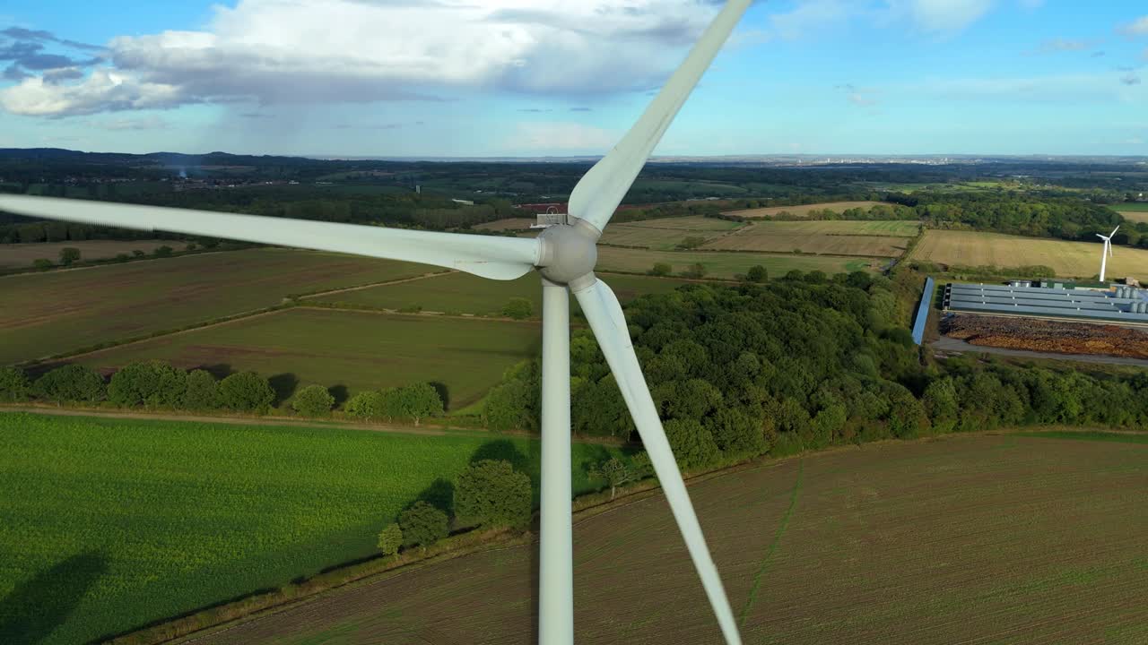 Drone footage of wind turbines generating electricity in scenic countryside with hills, farms, and valleys near Leicester, England