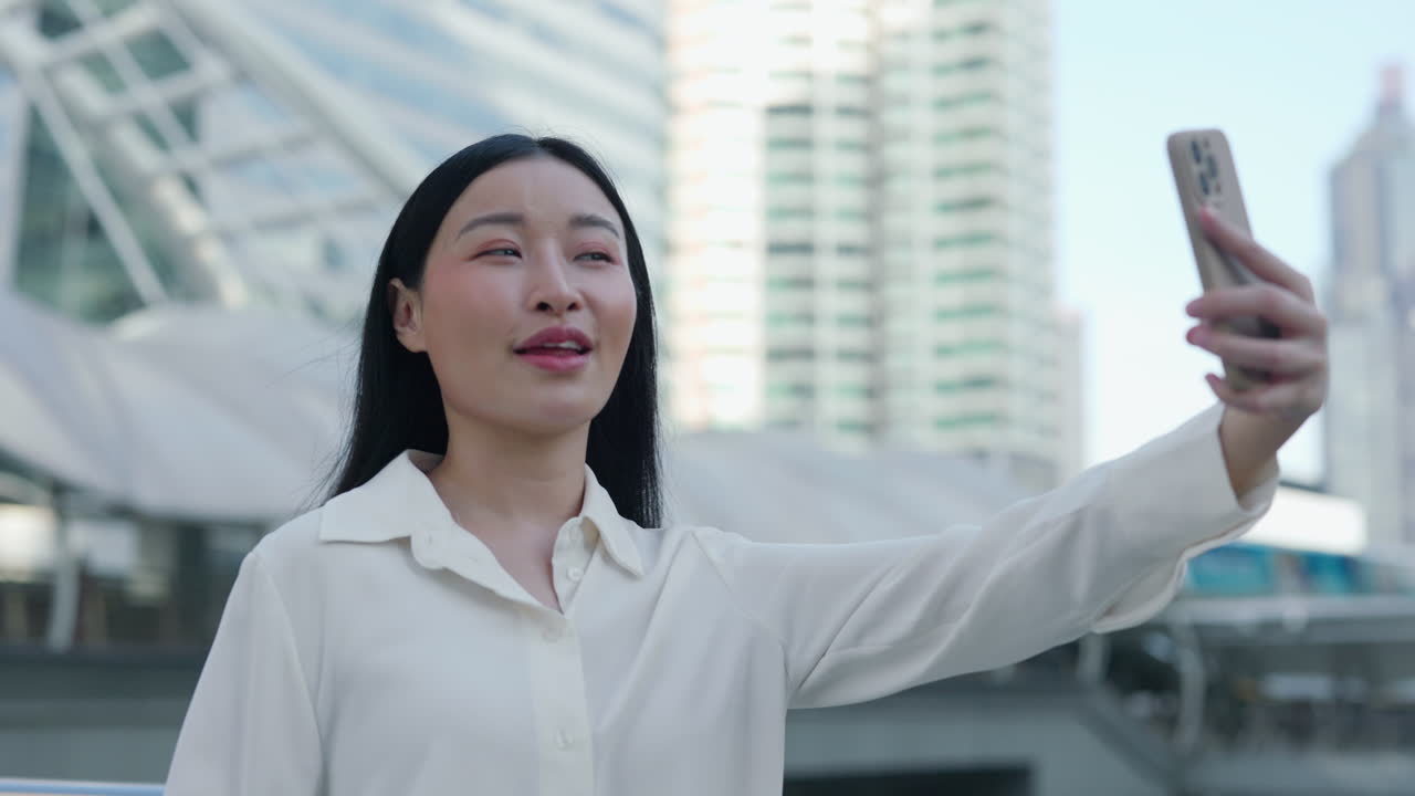 Young Asian woman taking a selfie or making a video call in a modern city