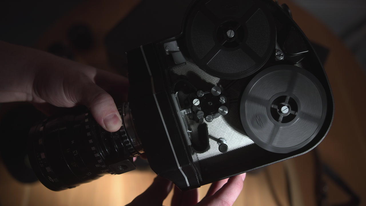 Hands Threading Vintage Film Reel Camera In Dim Studio Light, Filmmaker Carefully Loads And Inspects Tactile . Media