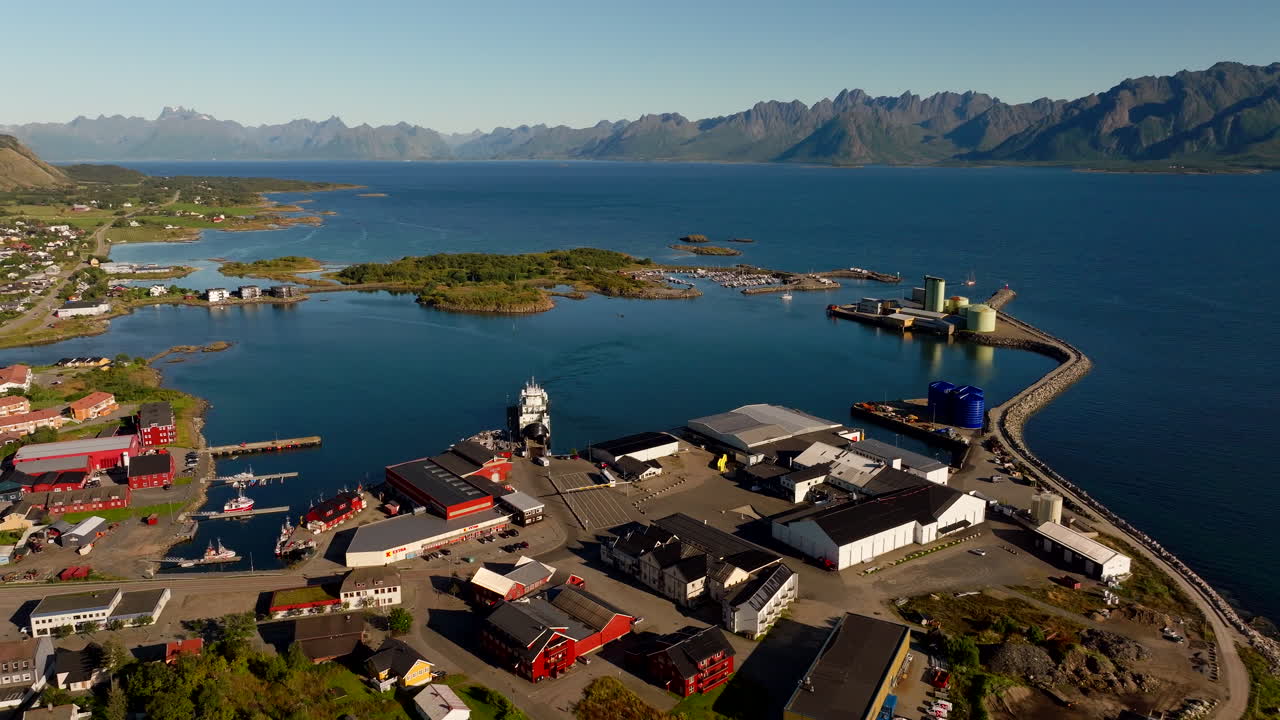 Aerial drone view of Melbu harbor with Lofoten islands in background on sunny day, Hadsel, Norway
