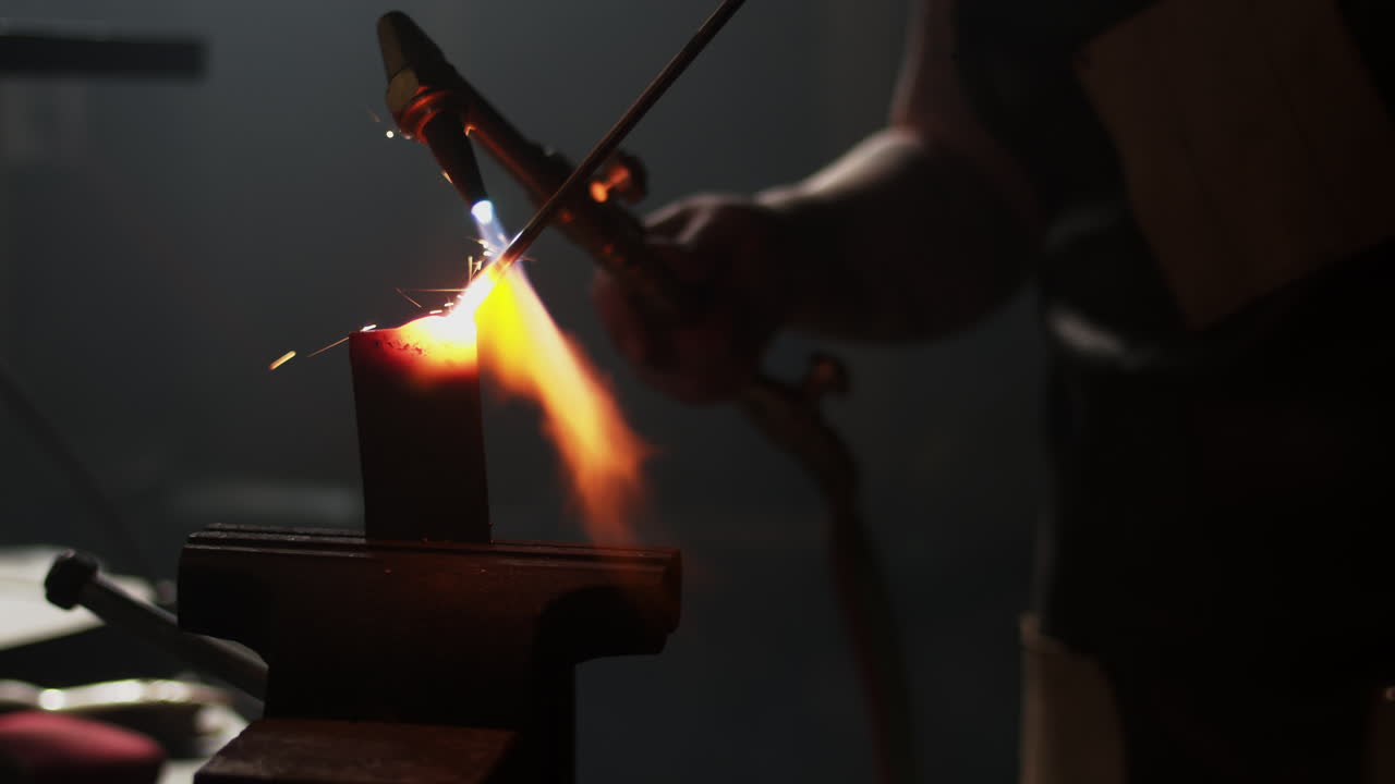 Røde, varme gnister flyr mens smeden sveiser sammen to metallstykker.