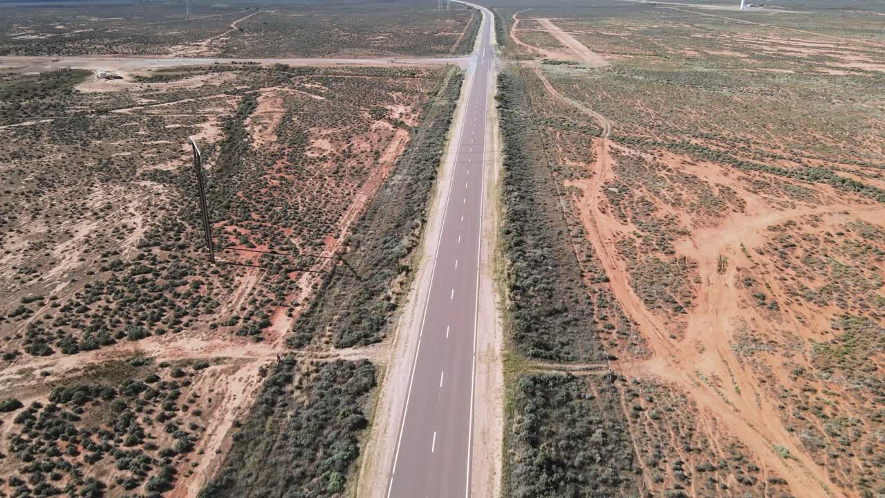 antena de drones sobre carretera desértica en australia para revelar energías renovables de parques eólicos