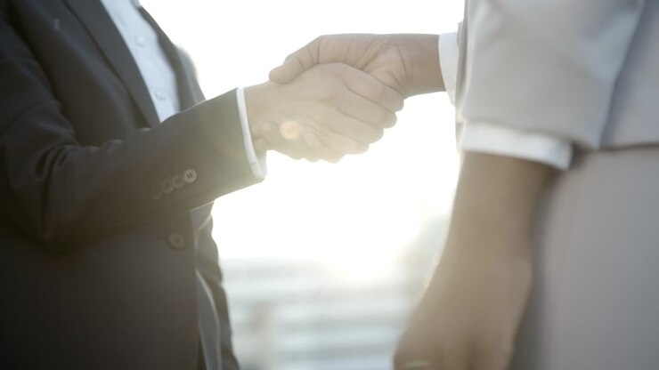 Slow motion shot of people shaking hands against sunset