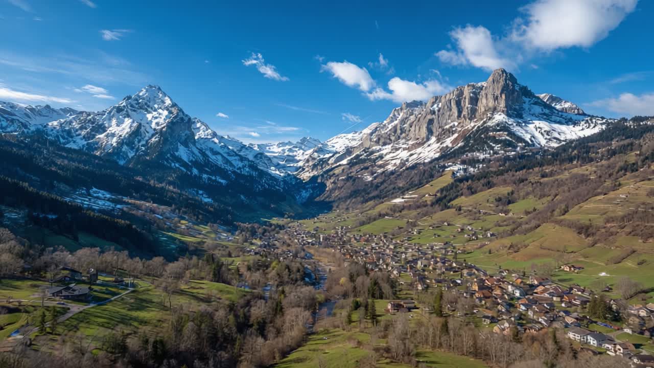 A Stunning Panoramic View of Snow-Capped Mountains and Lush Green Valleys Under a Clear Blue Sky, Showcasing the Beauty of Nature's Landscape