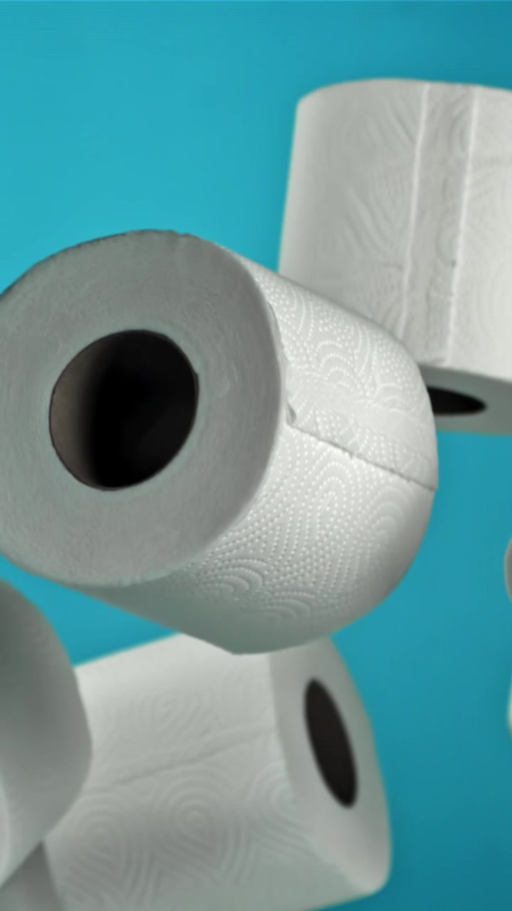 White Toilet Paper Rolls Floating Against a Blue Background