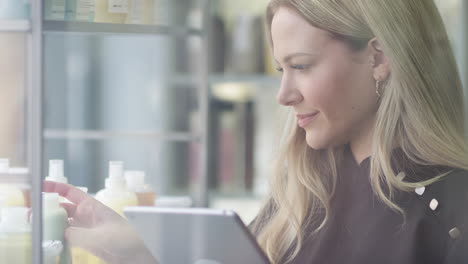 female business owner in hairdressing salon with digital tablet checking beauty products