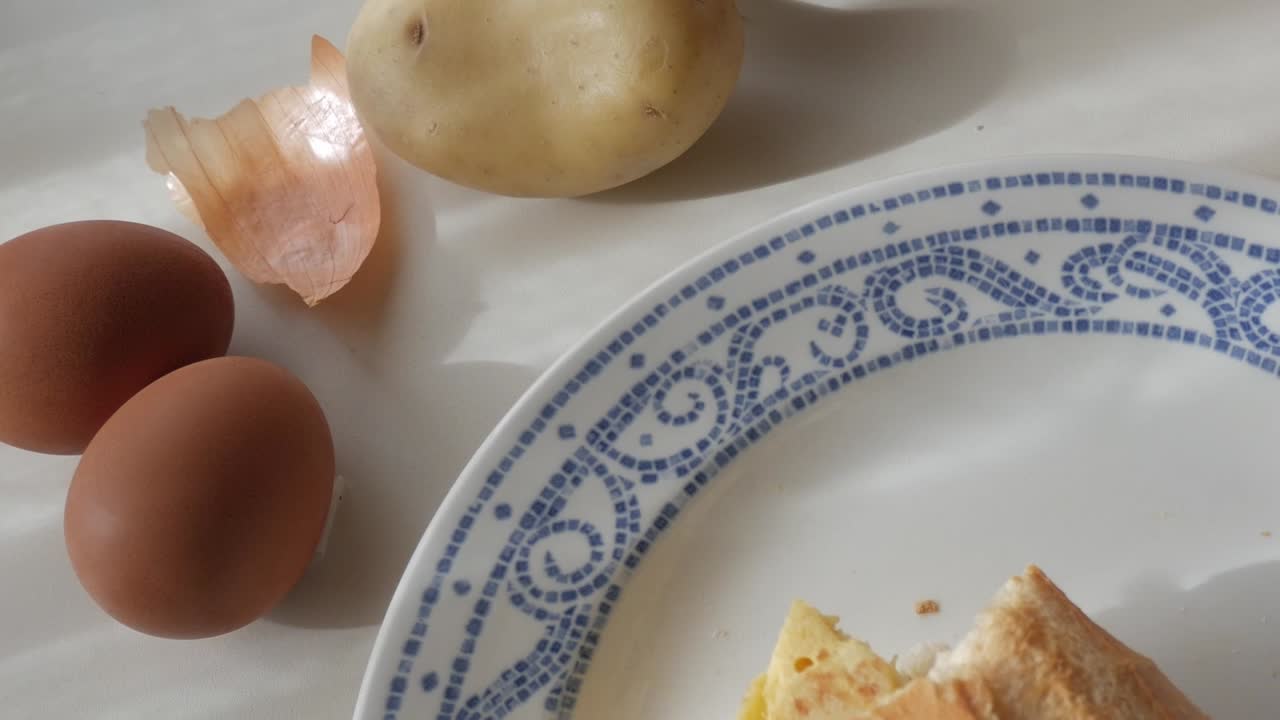 A couple of eggs, a potato, and a peeled onion skin on a plate for cooking tortilla