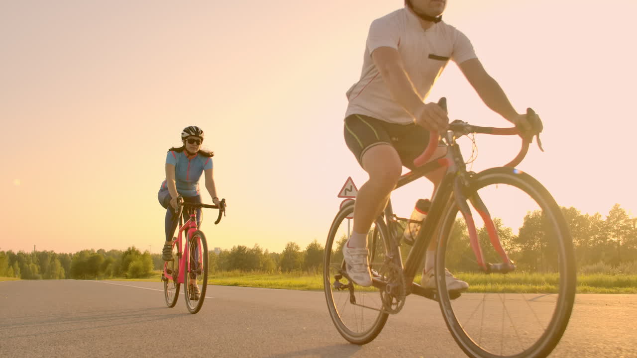 Steadicam shot of mountain biking couple riding on bike trail at sunset doing high.