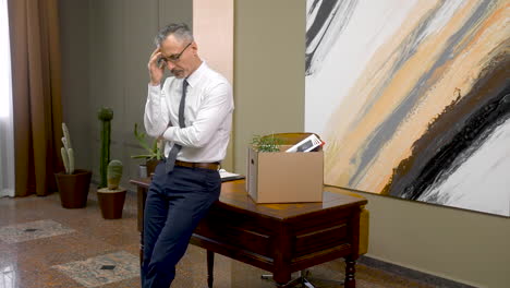 worried man after his resignation with his personal stuff on a box