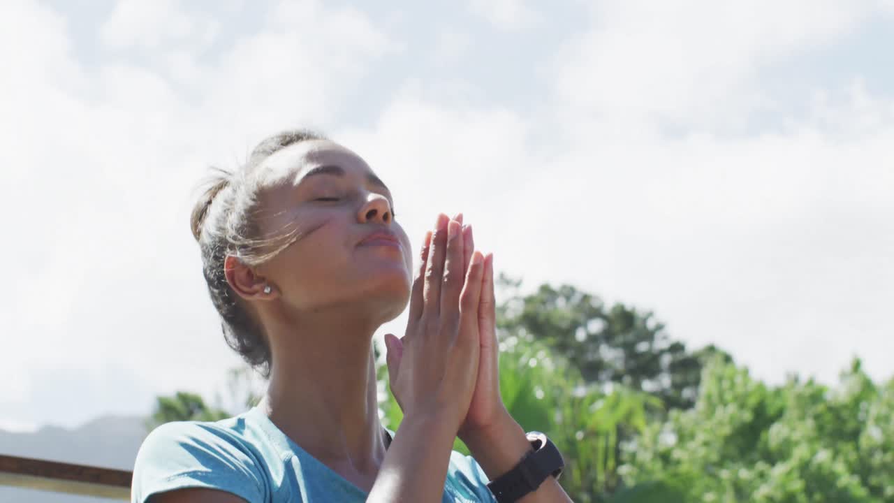 primer plano de una mujer biracial relajada sentada en la terraza y meditando
