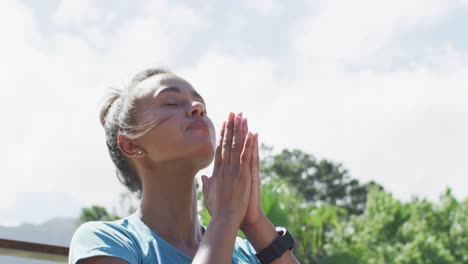 primer plano de una mujer biracial relajada sentada en la terraza y meditando