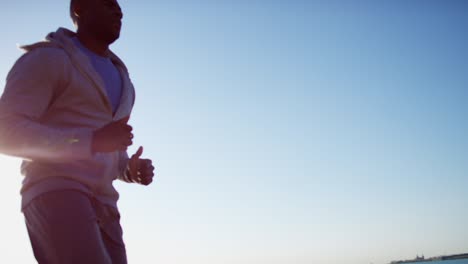 hombre étnico corriendo y estirándose en la llamarada del sol